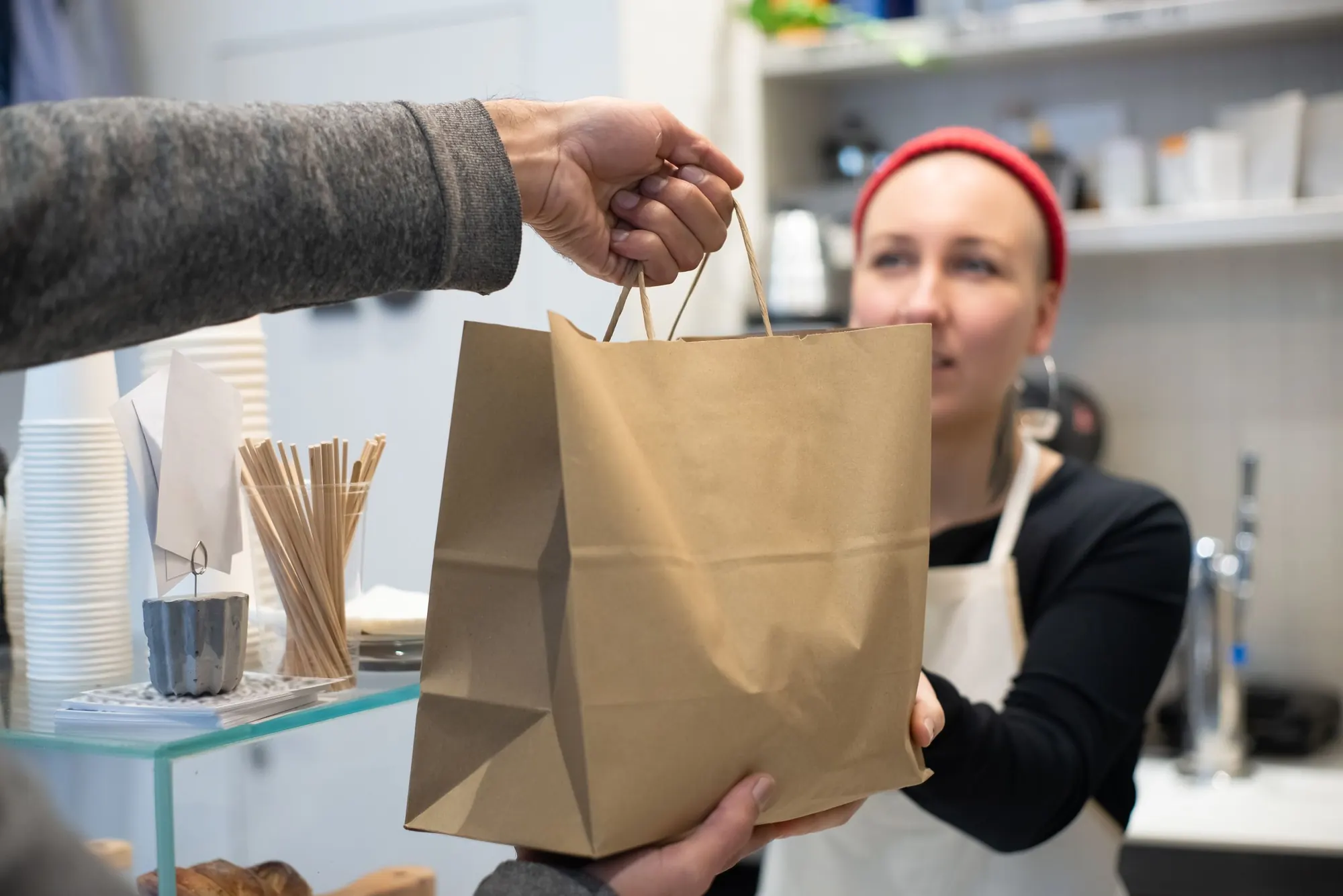 A paper bag handed over a bakery counter